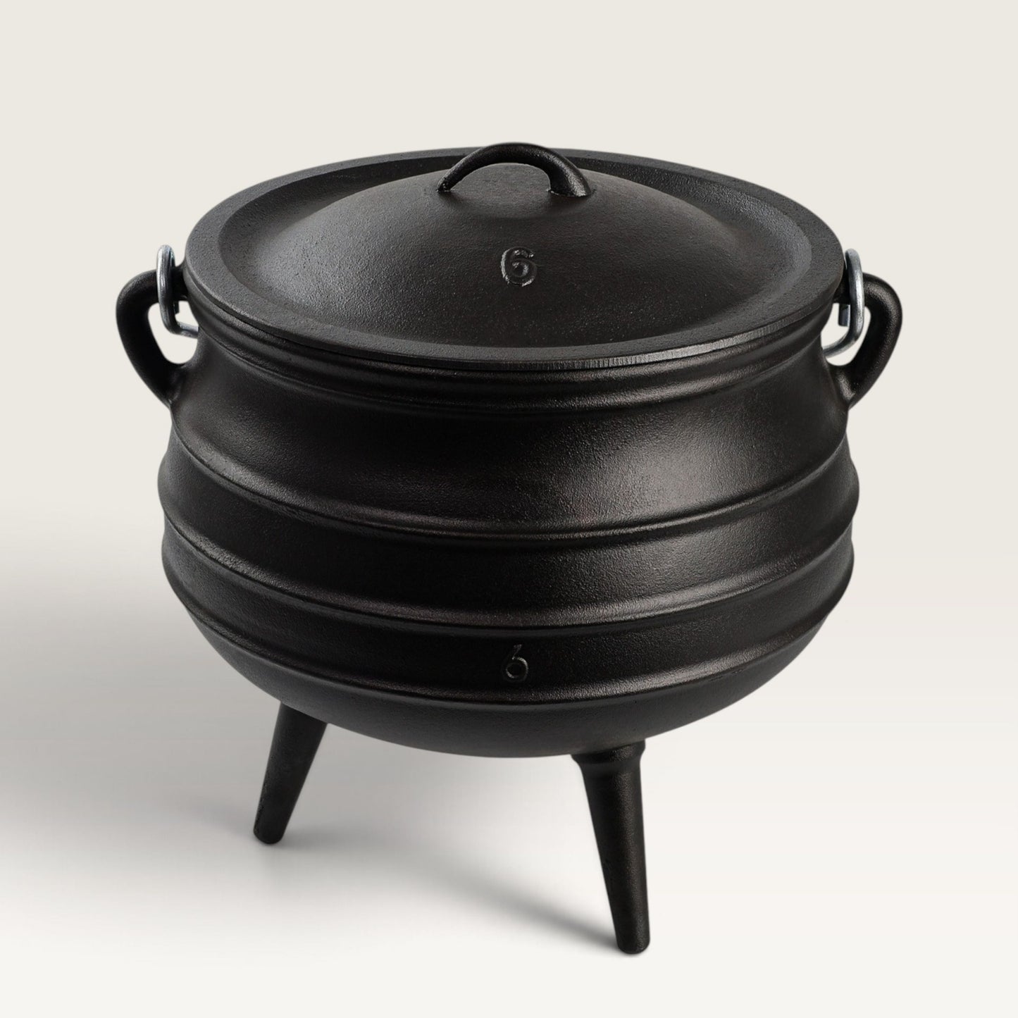 A black cast iron cauldron-style Dutch oven with a lid, side handles, and three legs, photographed on a clean light gray studio background. 14 qt potjie