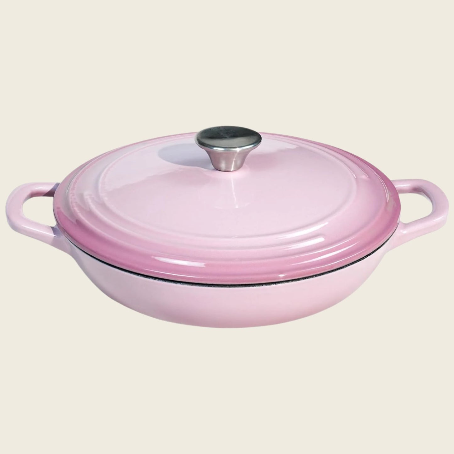 A pink enameled cast iron braiser with a lid, featuring a round shape and two handles.