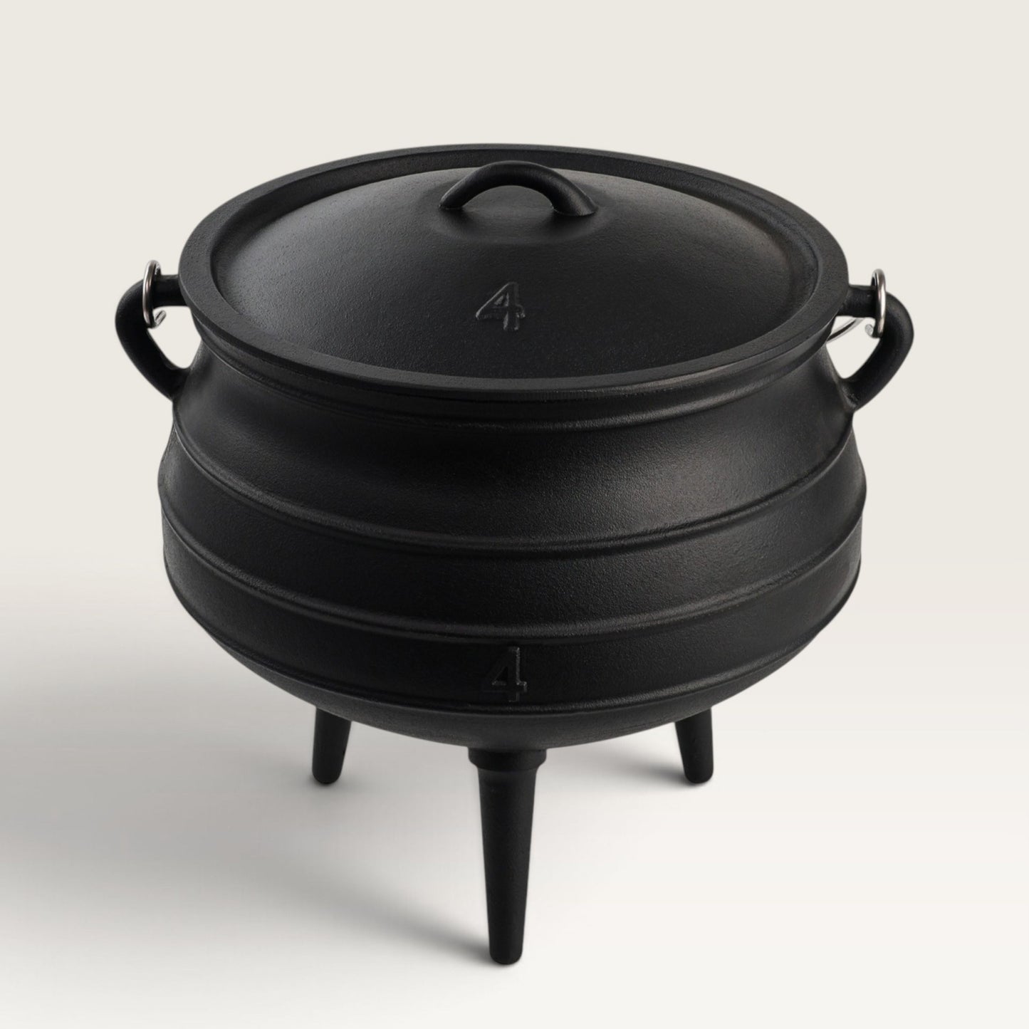 A black cast iron cauldron-style pot with a lid, side handles, and three legs, photographed on a clean light gray studio background. 10 qt potjie