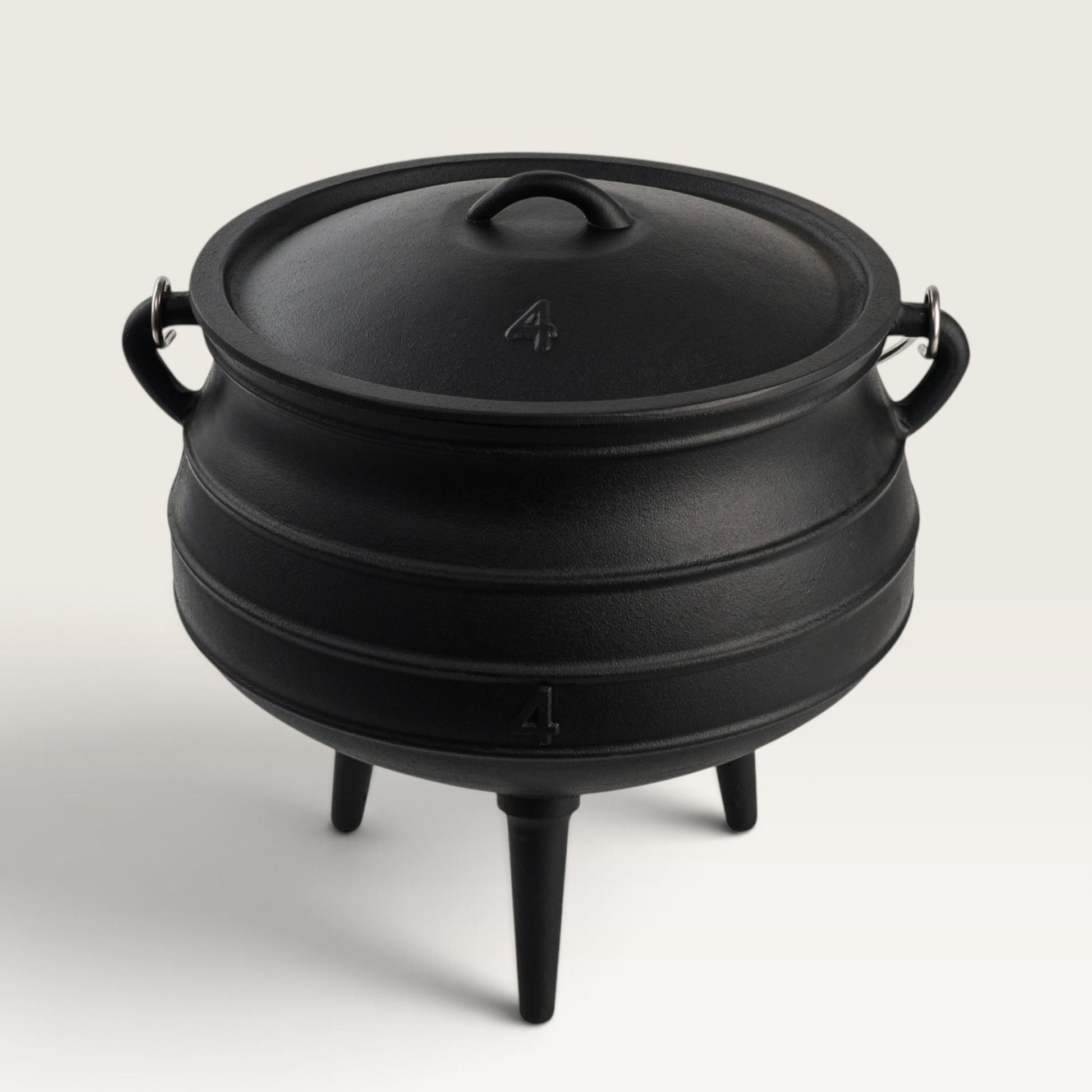 A black cast iron cauldron-style pot with a lid, side handles, and three legs, photographed on a clean light gray studio background. 10 qt potjie