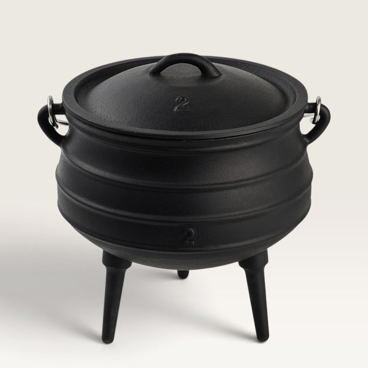 A black cast iron cauldron-style pot with a lid, side handles, and three legs, photographed on a clean light gray studio background. 6 qt Potjie