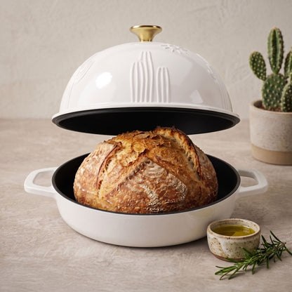 Pearl White cast iron bread oven with domed lid, open base holding rustic loaf, pearl white