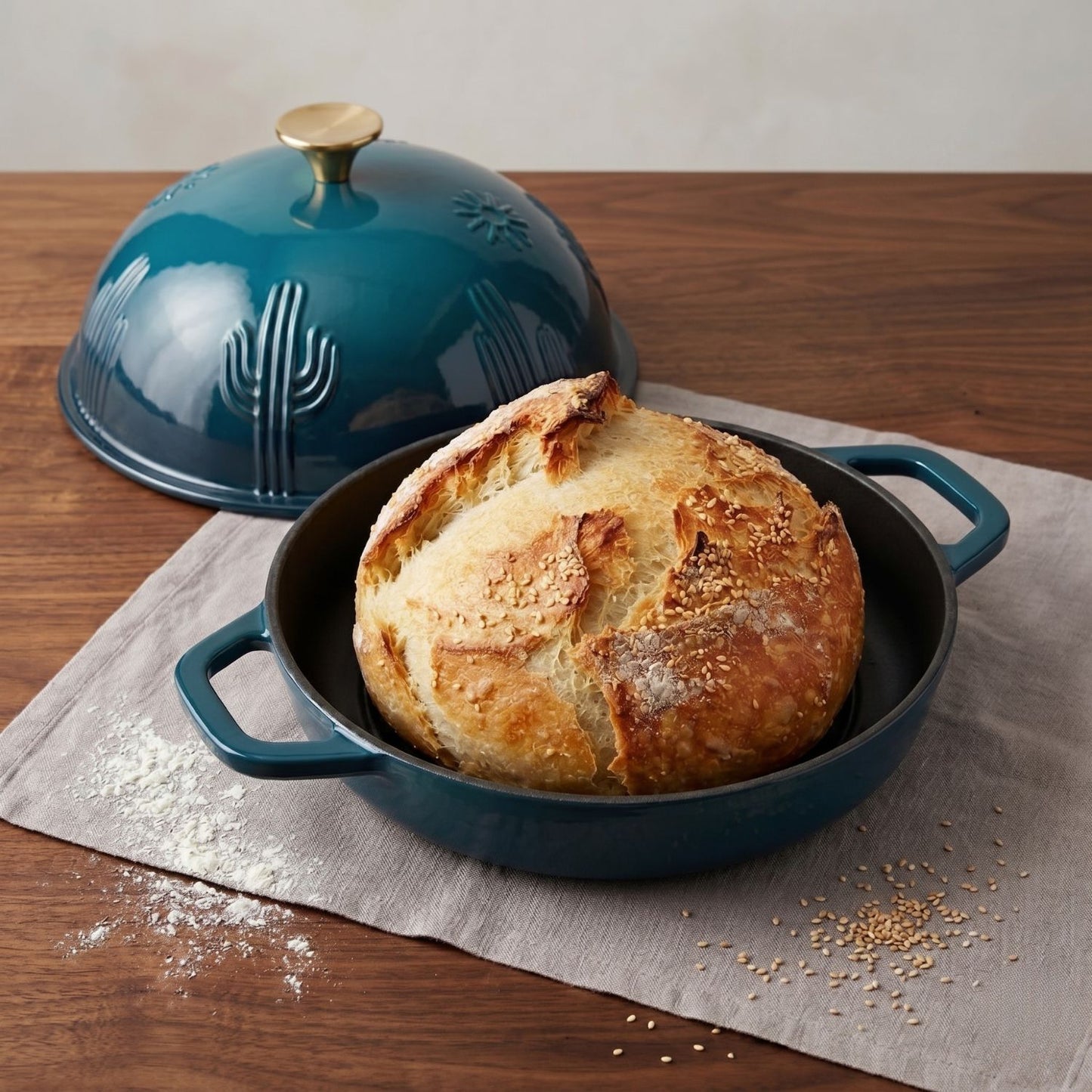 Teal enamel bread oven with domed lid open, holding a round loaf in the pan.