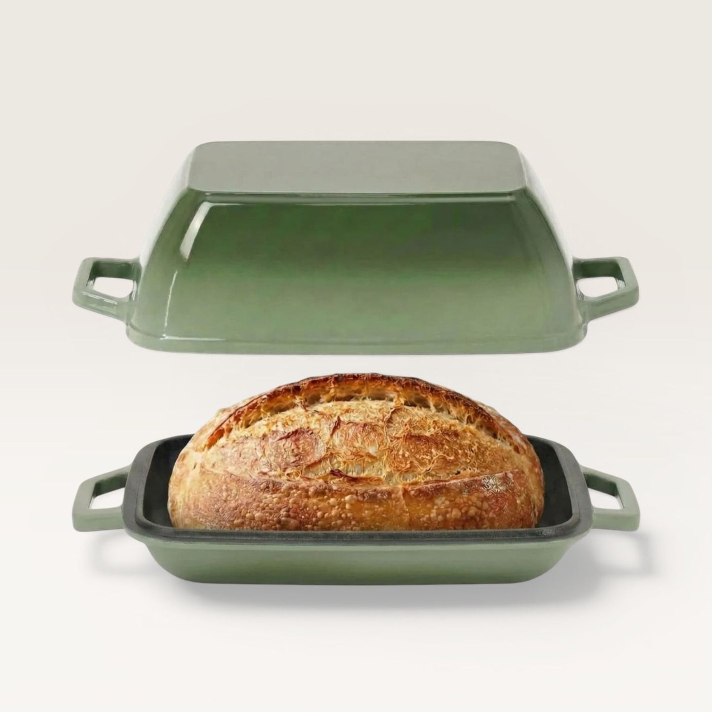 Sage green oval bread oven with lid and side handles, holding a baked loaf