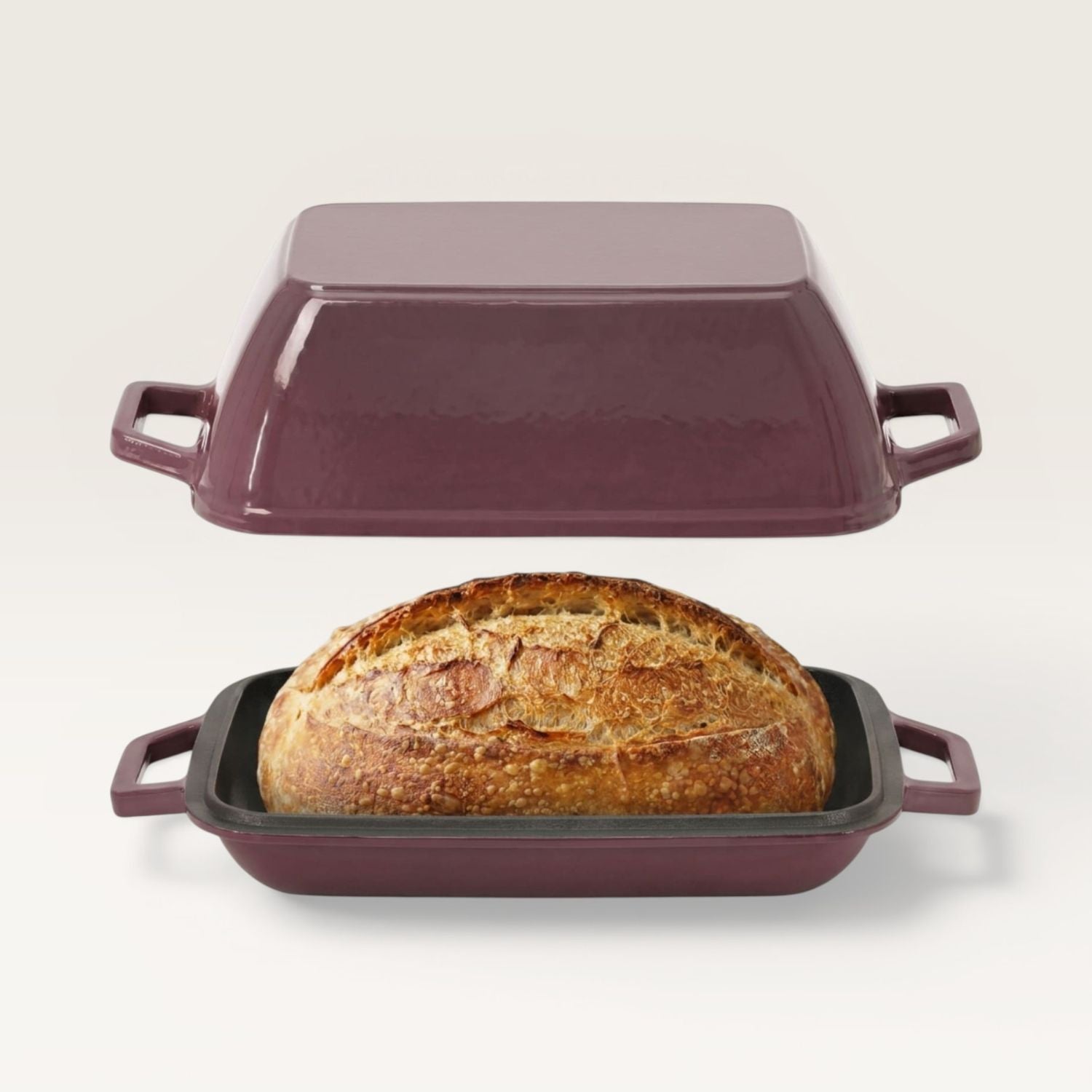 Plum purple oval bread oven with lid, holding a loaf in a black base tray