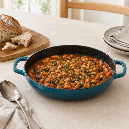 Dark Cyan shallow braiser with black interior and loop handles, filled with lentil stew