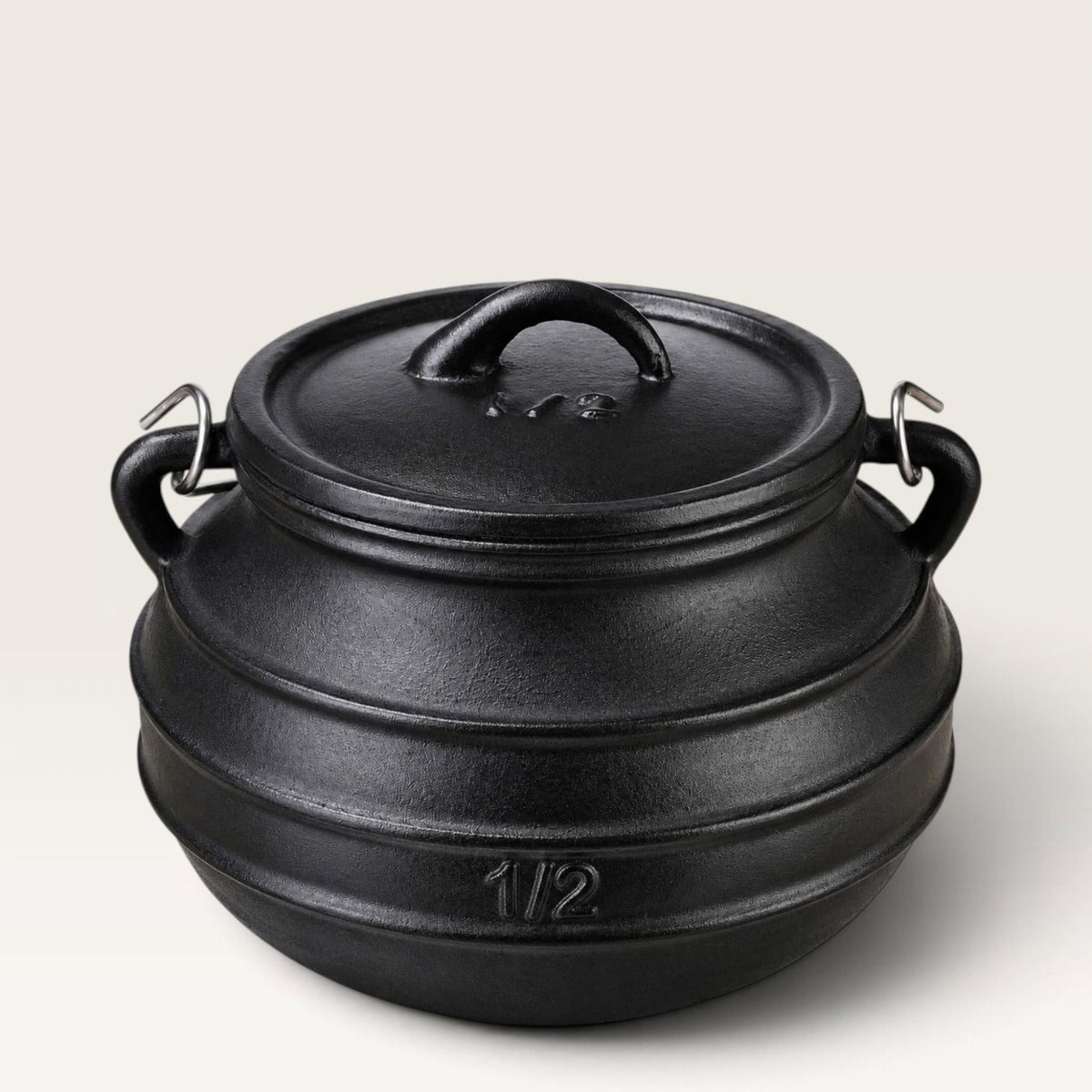 A black cast iron cauldron bean pot with a lid, featuring two side handles and a small embossed '1/2' marking on the front, set against a light gray background. 2 qt