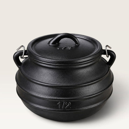 A black cast iron cauldron bean pot with a lid, featuring two side handles and a small embossed '1/2' marking on the front, set against a light gray background. 2 qt