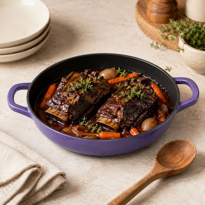 Iris Purple essential shallow braiser with two handles, filled with braised meat and carrots