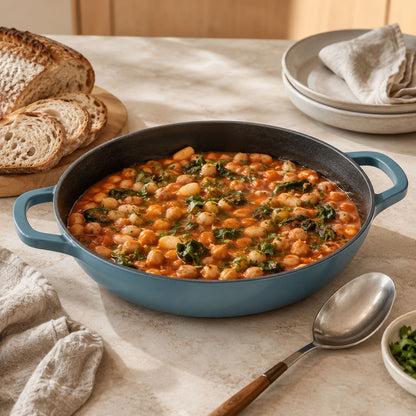 slate blue shallow braiser with black interior and handles, filled with beans and greens