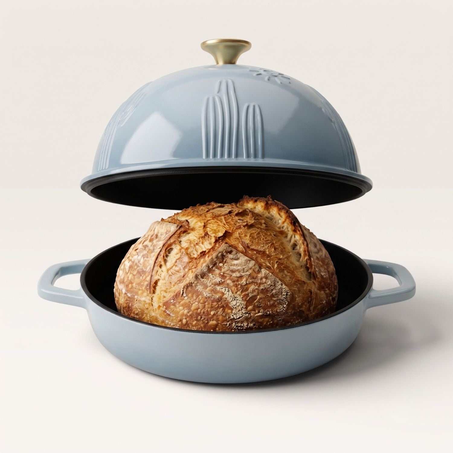 Light blue bread oven with clear domed lid holding a whole baked loaf