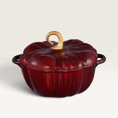 A glossy burgundy red pumpkin-shaped enameled cast iron pot with a matching lid and a light wood handle, shown on a clean off-white background.