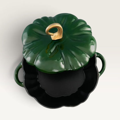 A glossy deep green pumpkin-shaped lidded pot with a gold-toned stem handle, shown open to reveal a black interior, on a clean off-white background.
