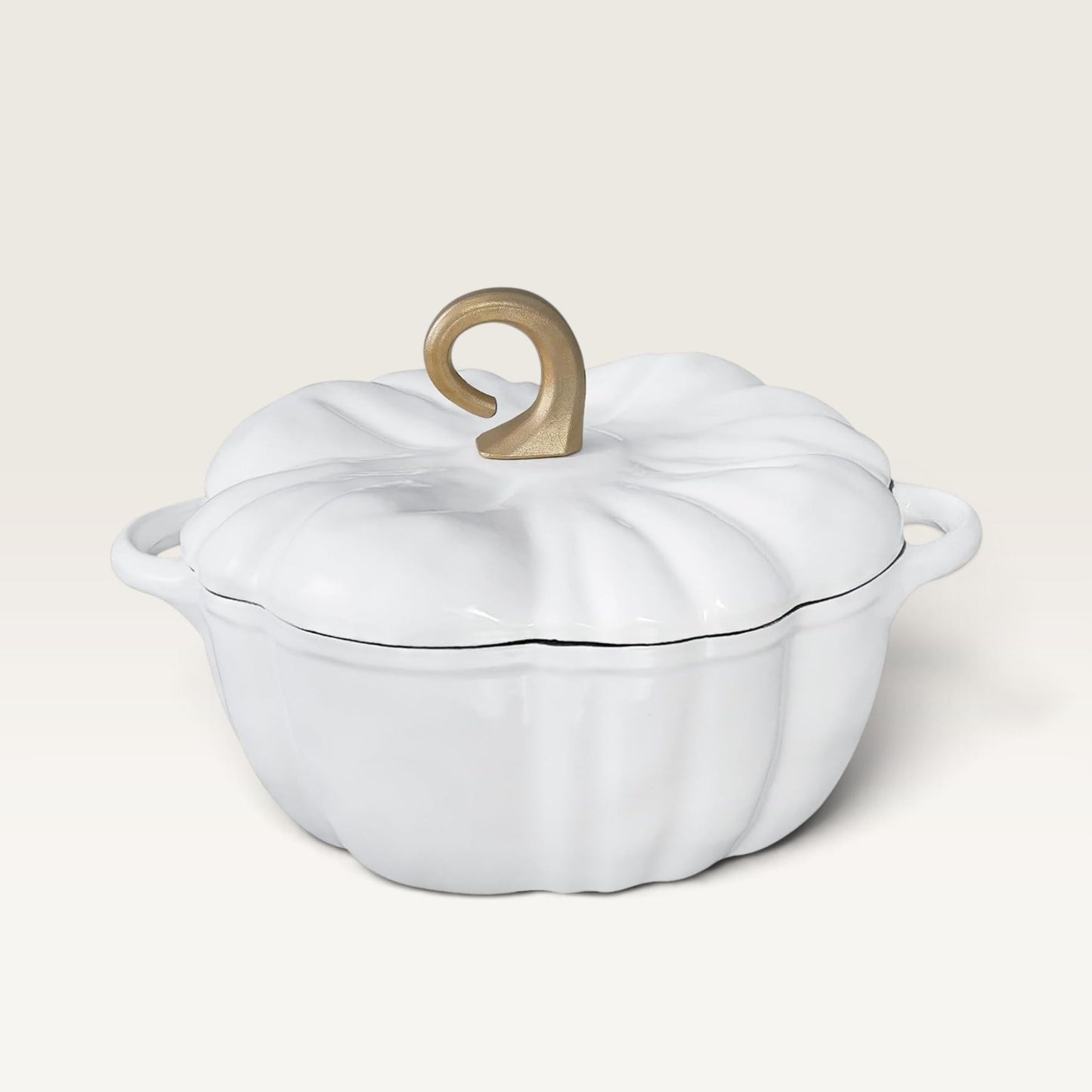 A pearl white enameled cast iron Dutch oven shaped like a pumpkin, featuring a ribbed lid with a decorative gold-colored handle and side handles, set against a solid cream background.