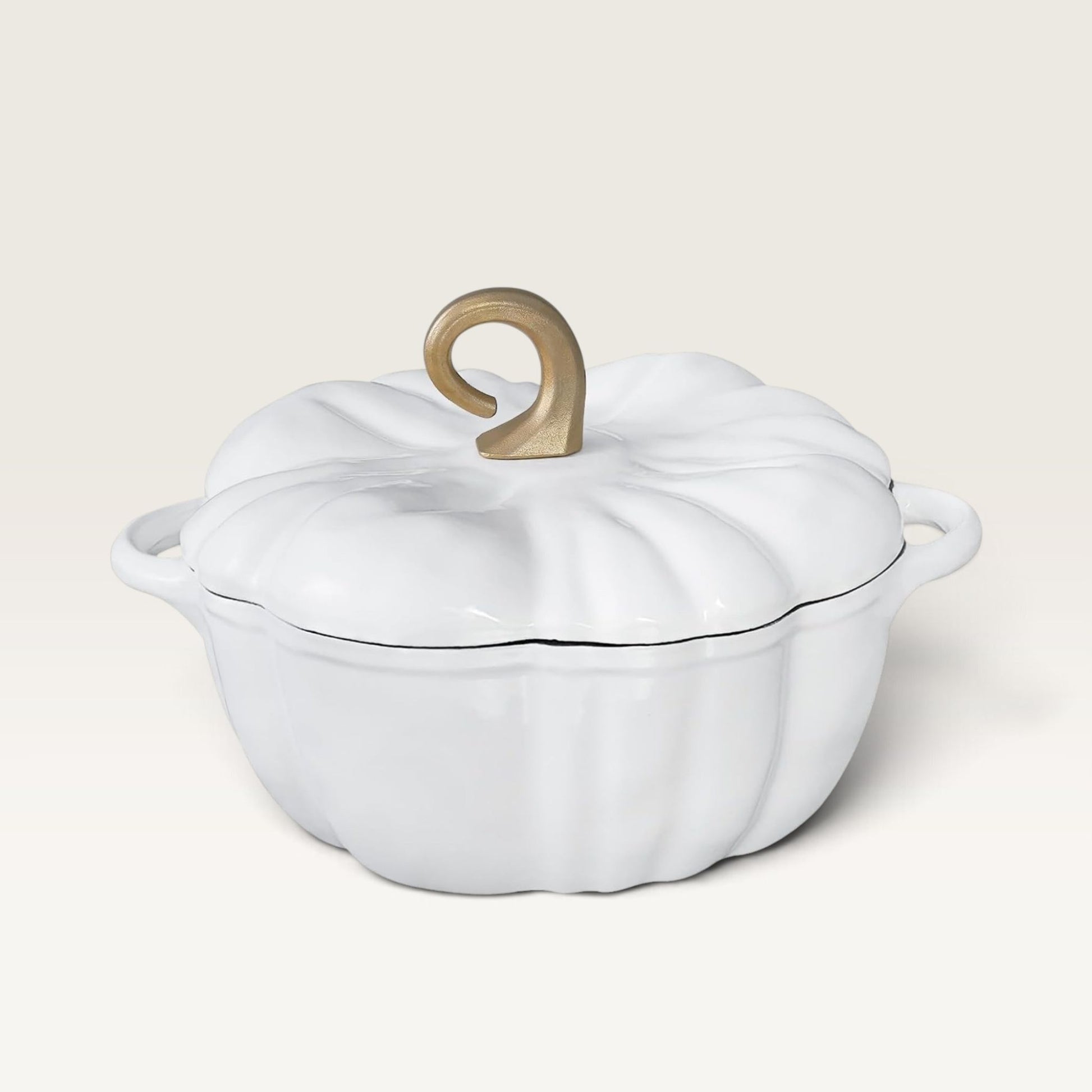 A pearl white enameled cast iron Dutch oven shaped like a pumpkin, featuring a ribbed lid with a decorative gold-colored handle and side handles, set against a solid cream background.