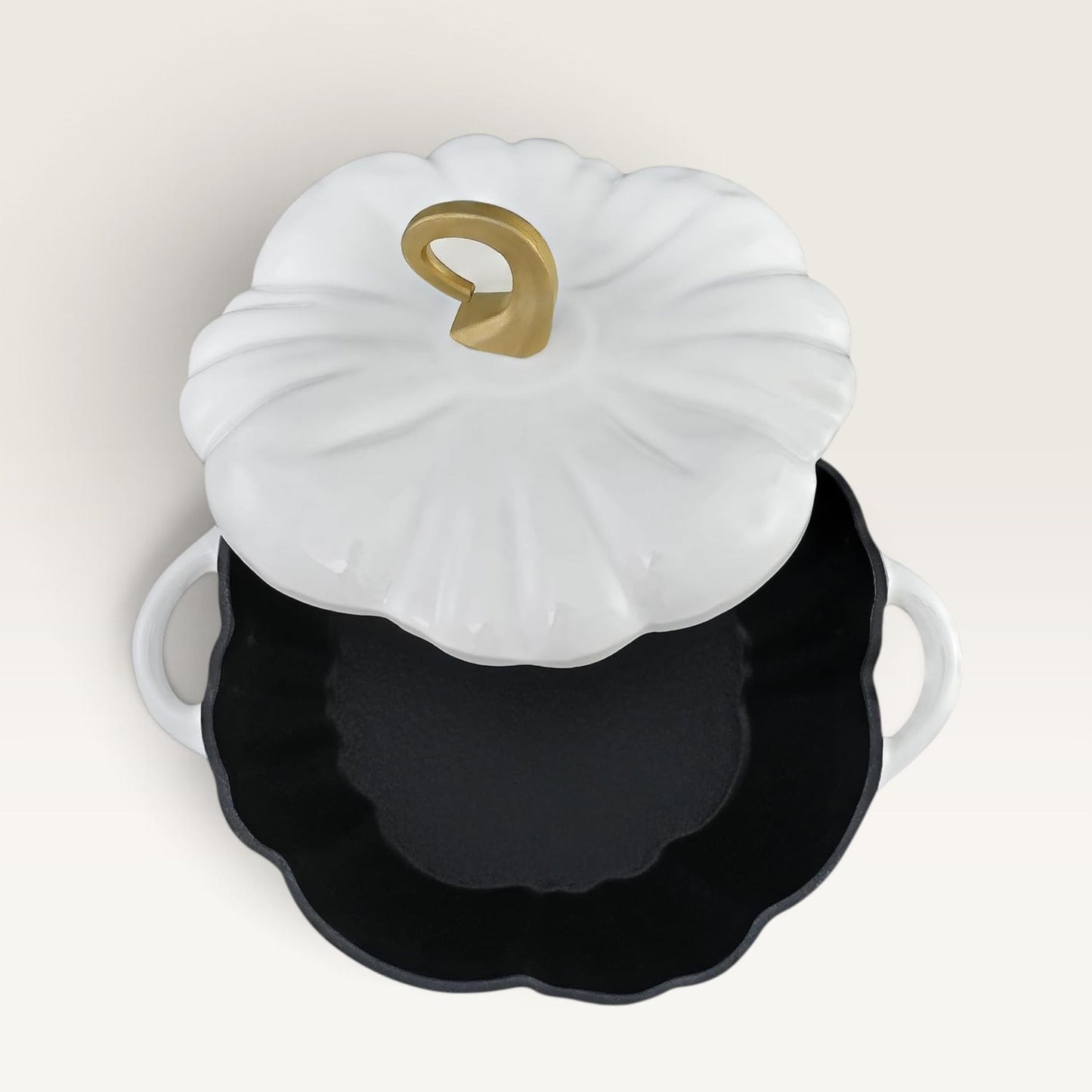 A decorative pumpkin-shaped lidded container or casserole dish with a pearl white ribbed lid, a gold stem detail, and a black interior, shown on a plain light beige background.
