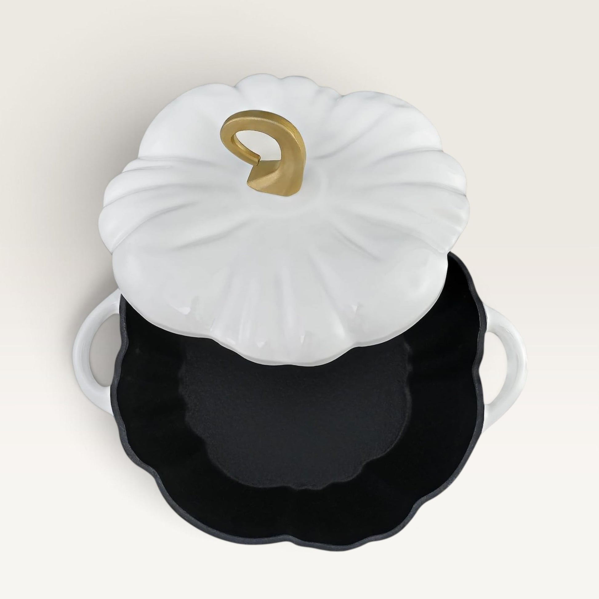 A decorative pumpkin-shaped lidded container or casserole dish with a pearl white ribbed lid, a gold stem detail, and a black interior, shown on a plain light beige background.