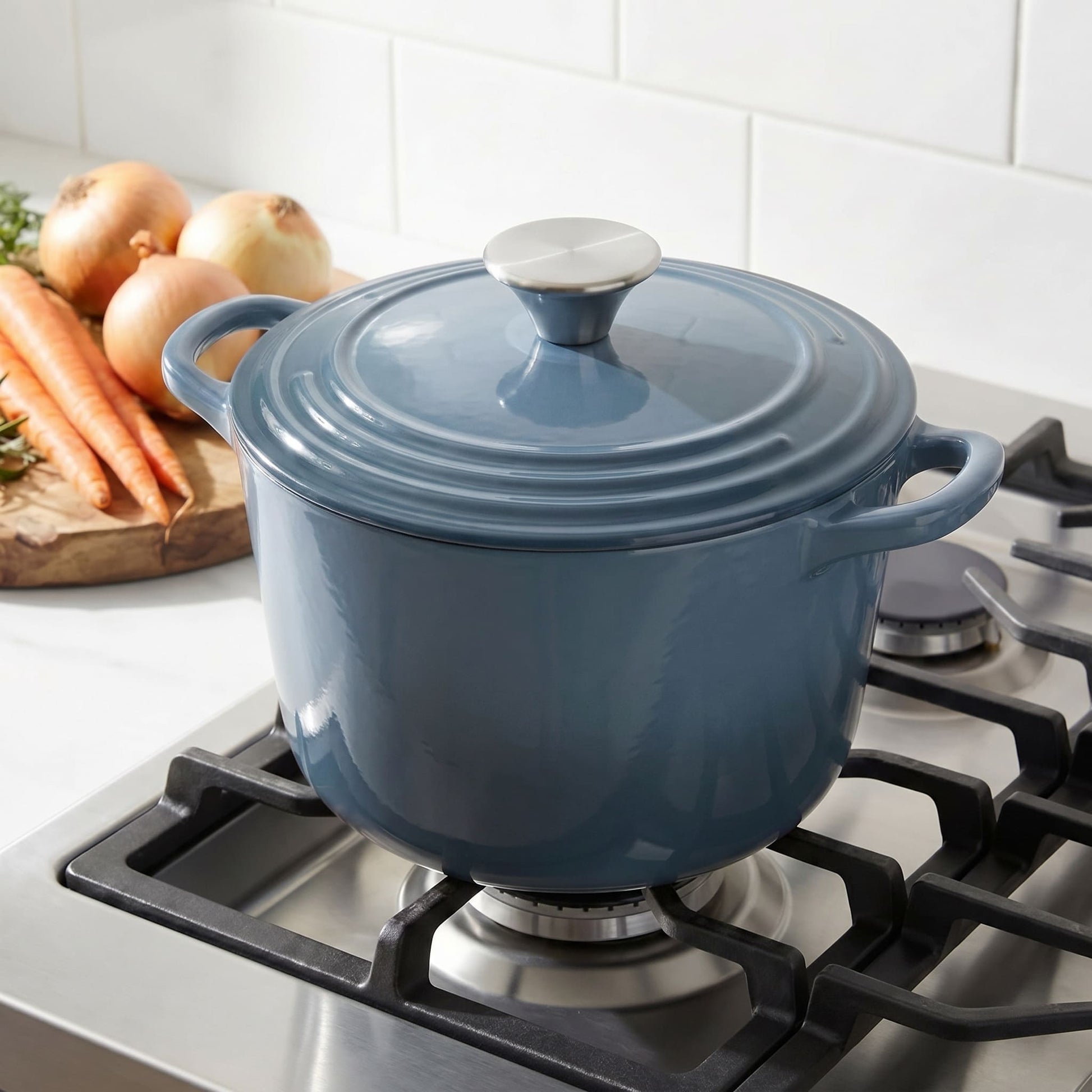 Blue deep dutch oven with lid on, on a gas stovetop with vegetables nearby